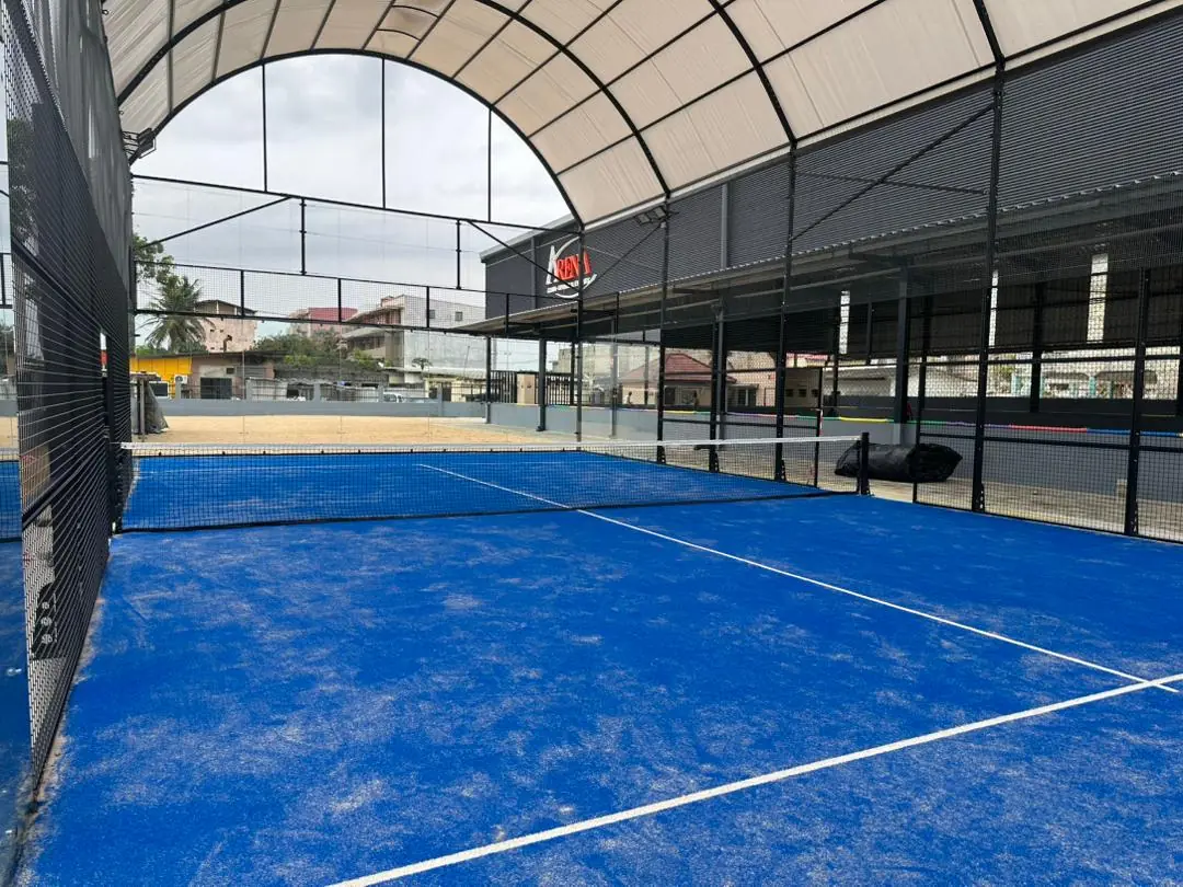 Court de padel bleu sous la toiture voûtée du complexe ARENA.